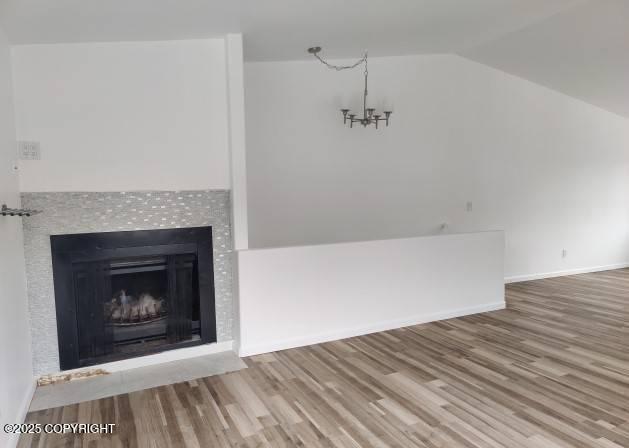 7141 Weimer Rd # 46, Anchorage, AK 99502 - unfurnished living room featuring lofted ceiling, wood finished floors, a chandelier, and a tile fireplace