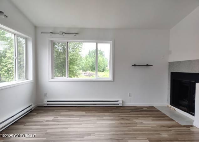 7141 Weimer Rd # 46, Anchorage, AK 99502 - unfurnished living room with baseboard heating, light wood-style floors, and a fireplace with flush hearth