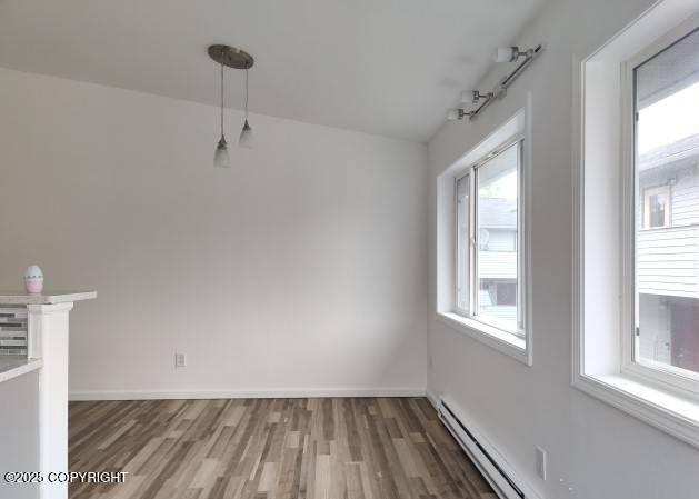 7141 Weimer Rd # 46, Anchorage, AK 99502 - unfurnished dining area featuring wood finished floors and a baseboard radiator