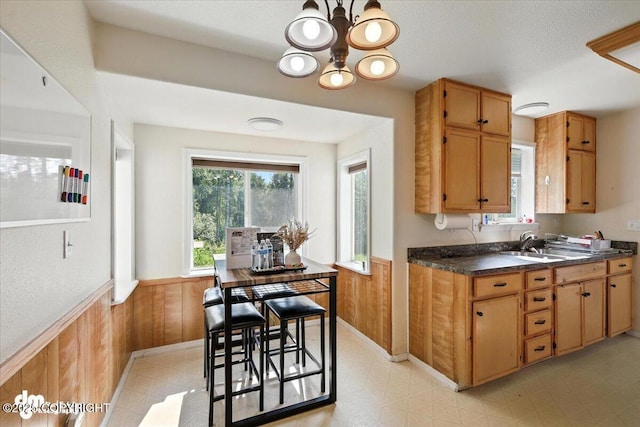 600 E Strathclyde Ln, Wasilla, AK 99654 - kitchen with light floors, a chandelier, a wainscoted wall, dark countertops, and wooden walls