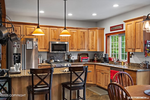 4051 Twilight Ln, Anchorage, AK 99516 - kitchen with appliances with stainless steel finishes, recessed lighting, a kitchen bar, hanging light fixtures, and dark stone counters