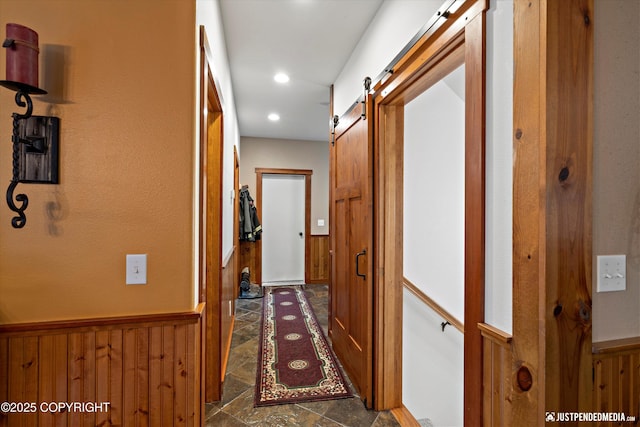 4051 Twilight Ln, Anchorage, AK 99516 - corridor with a barn door, wood walls, stone finish flooring, wainscoting, and recessed lighting