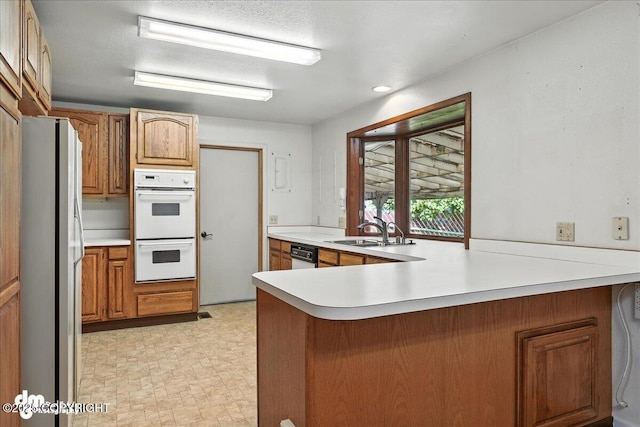 275 S Hoyt St, Anchorage, AK 99508 - kitchen featuring white appliances, a peninsula, light countertops, and brown cabinetry