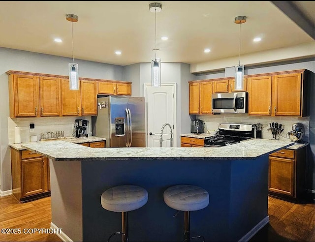 12297 Vista Ridge Loop # 55, Eagle River, AK 99577 - kitchen with appliances with stainless steel finishes, a kitchen island with sink, dark wood-type flooring, brown cabinetry, and backsplash