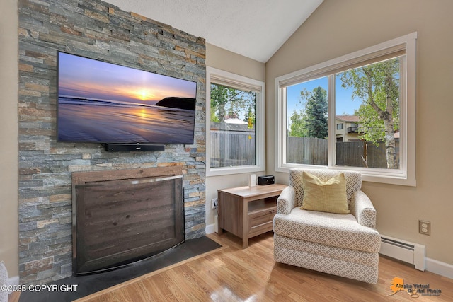 9606 Reliance Dr, Anchorage, AK 99507 - living area with a baseboard heating unit, vaulted ceiling, a stone fireplace, and wood finished floors