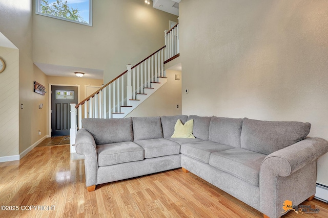 9606 Reliance Dr, Anchorage, AK 99507 - living room featuring a towering ceiling, wood finished floors, stairs, and baseboard heating