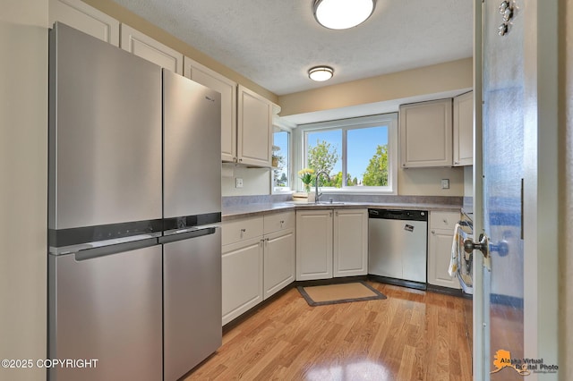9606 Reliance Dr, Anchorage, AK 99507 - kitchen with appliances with stainless steel finishes, light wood finished floors, a textured ceiling, and white cabinets