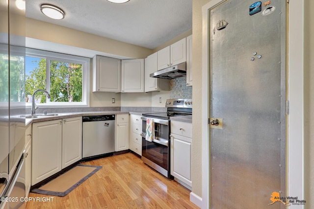9606 Reliance Dr, Anchorage, AK 99507 - kitchen featuring stainless steel appliances, under cabinet range hood, light wood-type flooring, and white cabinetry