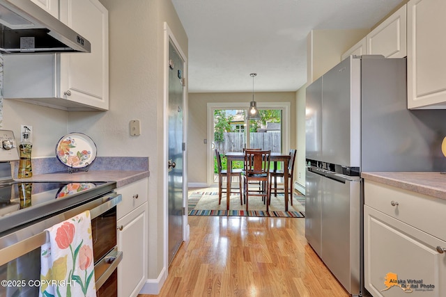 9606 Reliance Dr, Anchorage, AK 99507 - kitchen featuring appliances with stainless steel finishes, exhaust hood, light wood finished floors, and white cabinets