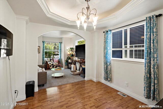2439 Maritime Loop, Anchorage, AK 99515 - living area with wood finished floors, a tray ceiling, a chandelier, arched walkways, and ornamental molding