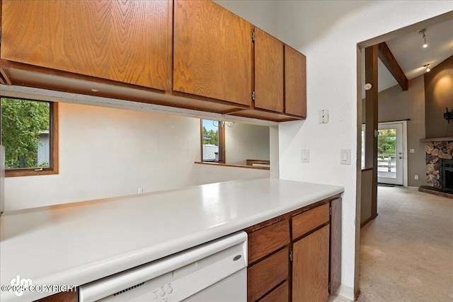 3681 E 20th Ave, Anchorage, AK 99508 - kitchen with white dishwasher, light countertops, light carpet, brown cabinets, and a fireplace