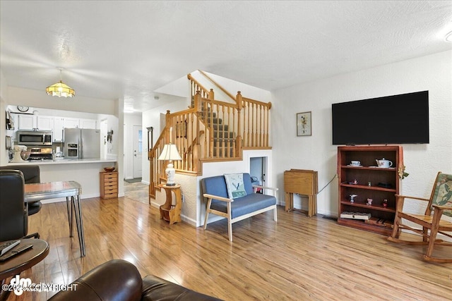 12313 Lake St # C-7, Eagle River, AK 99577 - living area with light wood-type flooring, stairway, and a textured ceiling