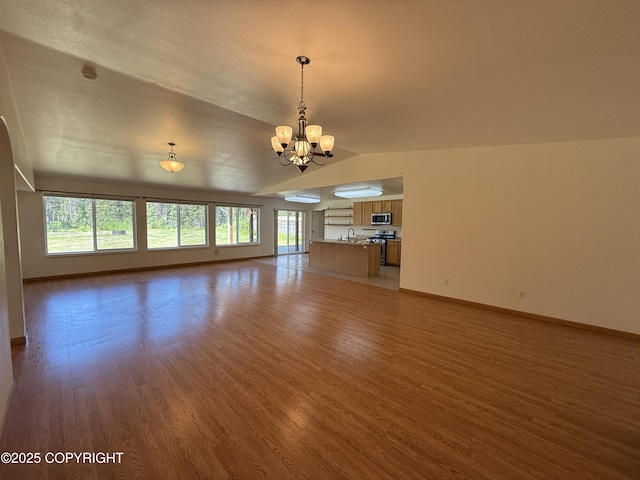 123 Green Valley St, Soldotna, AK 99669 - unfurnished living room with vaulted ceiling, a chandelier, healthy amount of natural light, and light wood finished floors