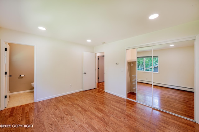 312 W Riverview Ave, Soldotna, AK 99669 - unfurnished bedroom with a baseboard radiator, light wood finished floors, recessed lighting, a closet, and ensuite bathroom
