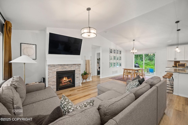 1302 E Esty Dr, Palmer, AK 99645 - living area featuring light wood-type flooring, lofted ceiling, a stone fireplace, and a chandelier