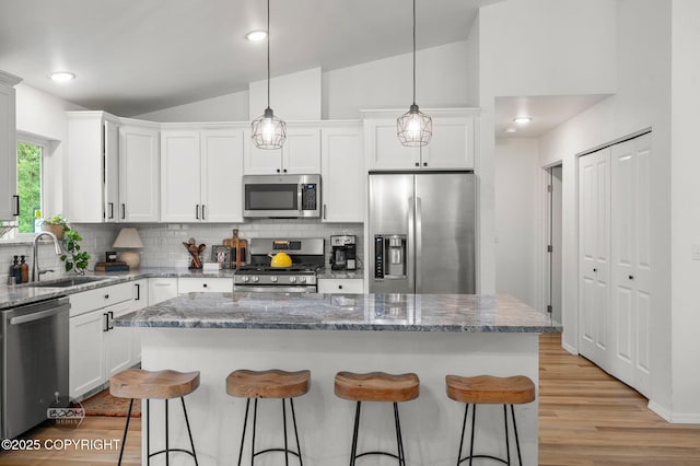1302 E Esty Dr, Palmer, AK 99645 - kitchen featuring stainless steel appliances, tasteful backsplash, a breakfast bar area, white cabinets, and light wood-style floors