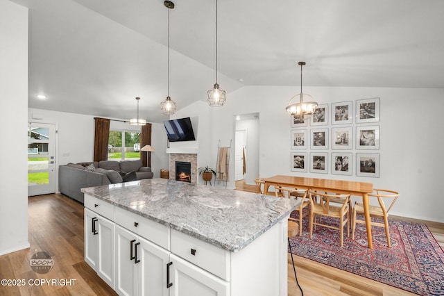 1302 E Esty Dr, Palmer, AK 99645 - kitchen with lofted ceiling, a fireplace, wood finished floors, a kitchen island, and white cabinets