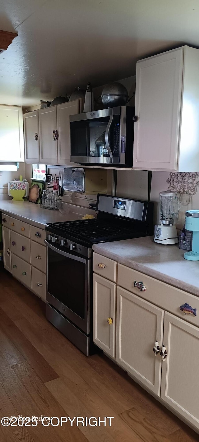 48105 Halverson Ave, Soldotna, AK 99669 - kitchen featuring stainless steel appliances, dark wood finished floors, light countertops, and white cabinetry