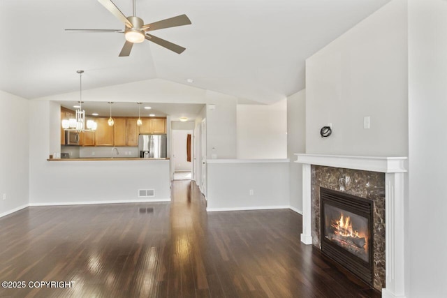 6218 Ophir Dr, Anchorage, AK 99504 - unfurnished living room with vaulted ceiling, a tile fireplace, dark wood-type flooring, ceiling fan, and a chandelier