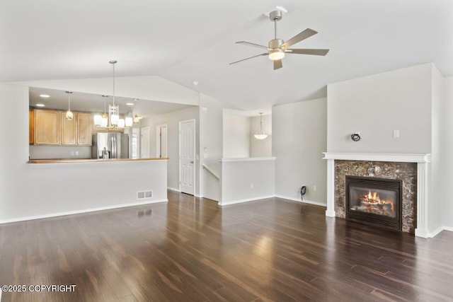 6218 Ophir Dr, Anchorage, AK 99504 - unfurnished living room with vaulted ceiling, a ceiling fan, dark wood finished floors, a tiled fireplace, and a chandelier