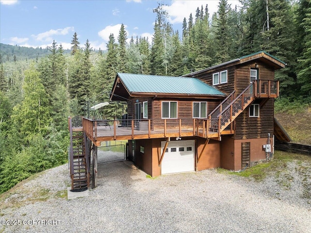 1685 Taroka Dr, Fairbanks, AK 99709 - chalet / cabin with stairway, a forest view, driveway, an attached garage, and a deck