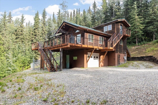 1685 Taroka Dr, Fairbanks, AK 99709 - view of front of house featuring gravel driveway, an attached garage, stairs, a deck, and a view of trees
