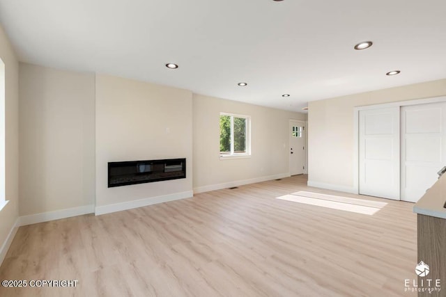 1401 E Holland Ave, Wasilla, AK 99654 - unfurnished living room with light wood finished floors, a glass covered fireplace, and recessed lighting