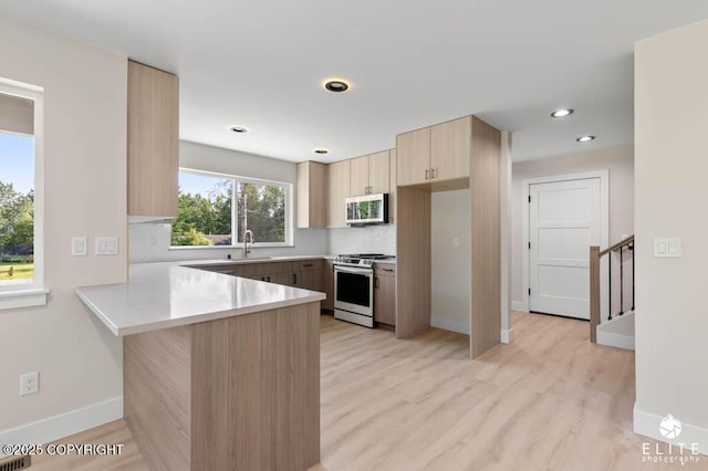 1401 E Holland Ave, Wasilla, AK 99654 - kitchen with appliances with stainless steel finishes, light brown cabinets, a peninsula, light wood finished floors, and light countertops