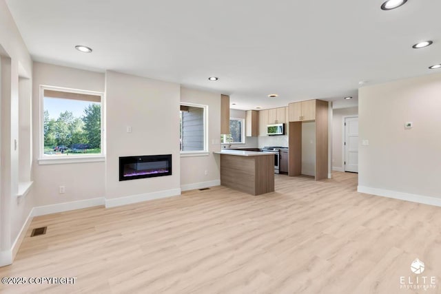 1401 E Holland Ave, Wasilla, AK 99654 - kitchen featuring stainless steel appliances, a peninsula, light wood-style flooring, open floor plan, and recessed lighting