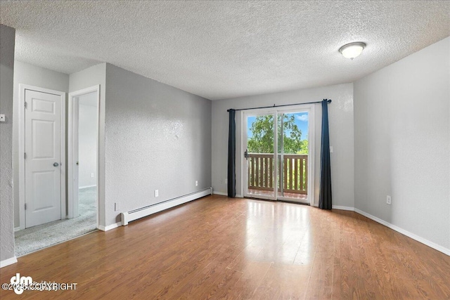 8203 Duben Ave, Anchorage, AK 99504 - unfurnished room with a baseboard heating unit, wood finished floors, a textured ceiling, and a textured wall