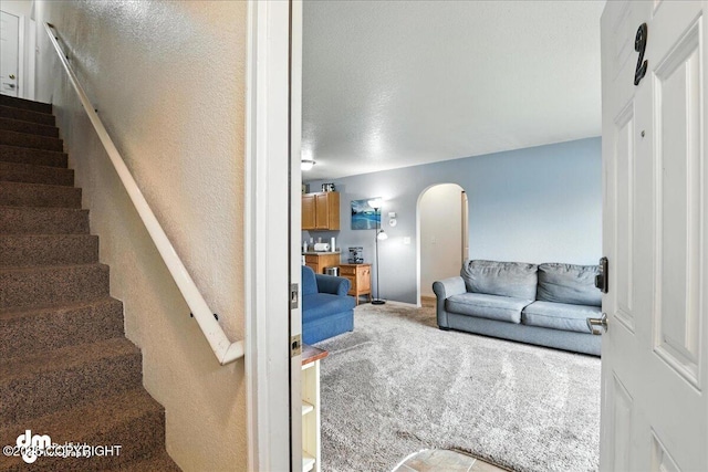 8203 Duben Ave, Anchorage, AK 99504 - living room featuring carpet, arched walkways, stairway, and a textured wall