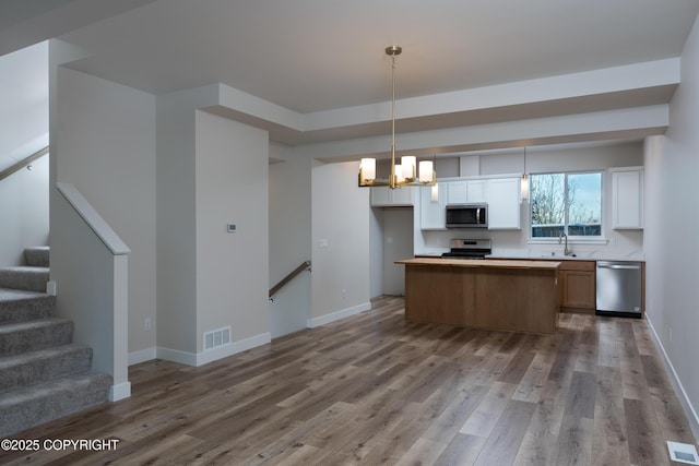 3680 Little Bear Pl Unit 8, Anchorage, AK 99504 - kitchen featuring appliances with stainless steel finishes, open floor plan, wood finished floors, a kitchen island, and a chandelier