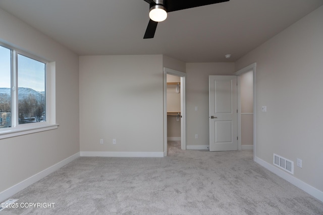 3680 Little Bear Pl Unit 8, Anchorage, AK 99504 - unfurnished bedroom with a walk in closet, carpet floors, a ceiling fan, a closet, and a mountain view