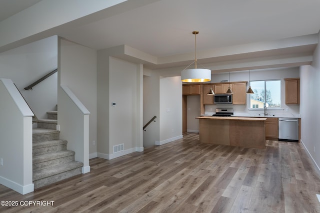 3680 Little Bear Pl Unit 8, Anchorage, AK 99504 - kitchen featuring stainless steel appliances, light wood-style floors, light countertops, hanging light fixtures, and a center island