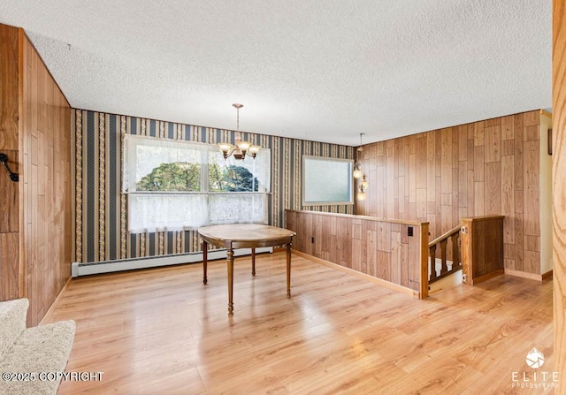 13440 Diggins Dr, Anchorage, AK 99515 - dining area featuring a textured ceiling, baseboard heating, a chandelier, wood finished floors, and healthy amount of natural light