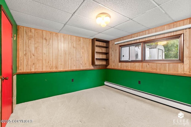 13440 Diggins Dr, Anchorage, AK 99515 - spare room featuring a baseboard radiator, wood walls, built in shelves, carpet, and a paneled ceiling