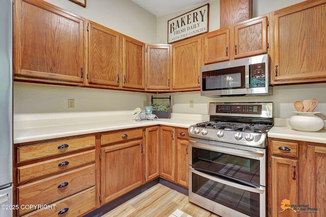 22479 Centurion Dr, Chugiak, AK 99567 - kitchen with appliances with stainless steel finishes, light countertops, light wood-style flooring, and brown cabinetry
