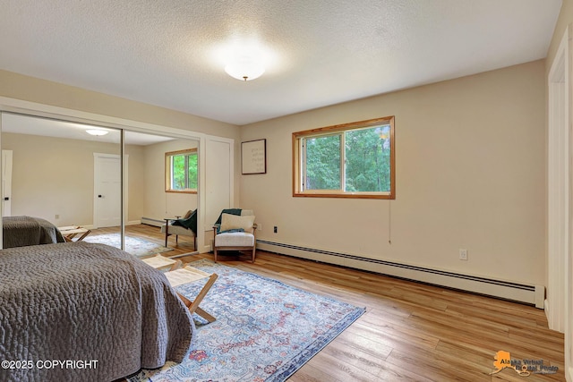 22479 Centurion Dr, Chugiak, AK 99567 - bedroom with baseboard heating, wood finished floors, a closet, and a textured ceiling