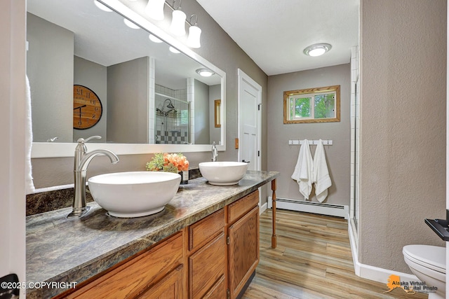 22479 Centurion Dr, Chugiak, AK 99567 - bathroom with a baseboard radiator, a stall shower, wood finished floors, double vanity, and a textured wall