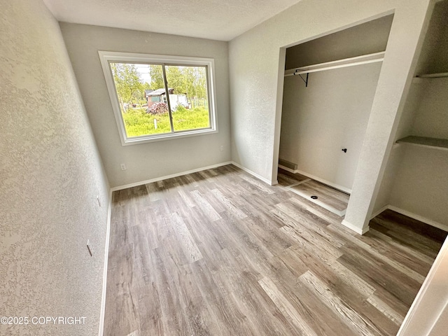 35870 Glory St, Soldotna, AK 99669 - unfurnished bedroom with wood finished floors, a closet, and a textured wall