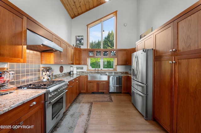 2500 W Highland Dr, Homer, AK 99603 - kitchen featuring appliances with stainless steel finishes, exhaust hood, high vaulted ceiling, light wood-style flooring, and brown cabinetry