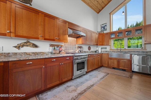 2500 W Highland Dr, Homer, AK 99603 - kitchen with appliances with stainless steel finishes, exhaust hood, high vaulted ceiling, light wood-style flooring, and brown cabinetry