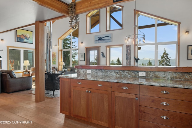 2500 W Highland Dr, Homer, AK 99603 - kitchen with open floor plan, brown cabinets, light wood-type flooring, light stone counters, and a high ceiling