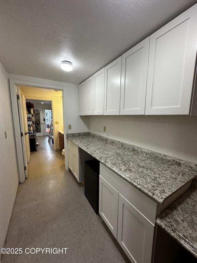 231 Main St, Seldovia, AK 99663 - kitchen featuring a textured ceiling, white cabinetry, tile patterned floors, and light stone counters