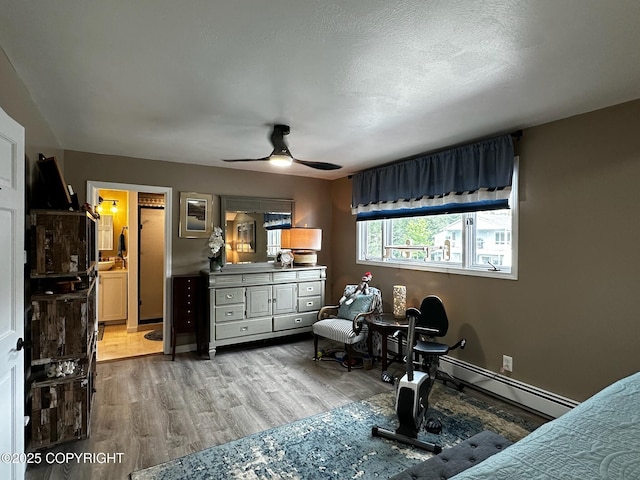 231 Main St, Seldovia, AK 99663 - bedroom with baseboard heating, wood finished floors, ceiling fan, and ensuite bath