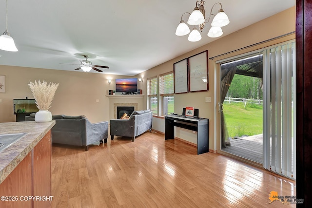 730 N Kimberly St, Wasilla, AK 99654 - living area featuring a glass covered fireplace, light wood-type flooring, a chandelier, and ceiling fan