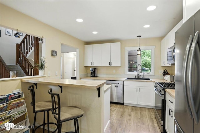 6622 Lakeway Dr, Anchorage, AK 99502 - kitchen with stainless steel appliances, wood counters, a kitchen bar, light wood-style floors, and recessed lighting