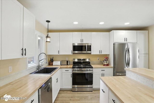 6622 Lakeway Dr, Anchorage, AK 99502 - kitchen with stainless steel appliances, white cabinets, hanging light fixtures, light wood-type flooring, and recessed lighting