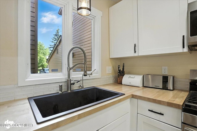 6622 Lakeway Dr, Anchorage, AK 99502 - kitchen featuring white cabinets, wooden counters, stainless steel microwave, and backsplash