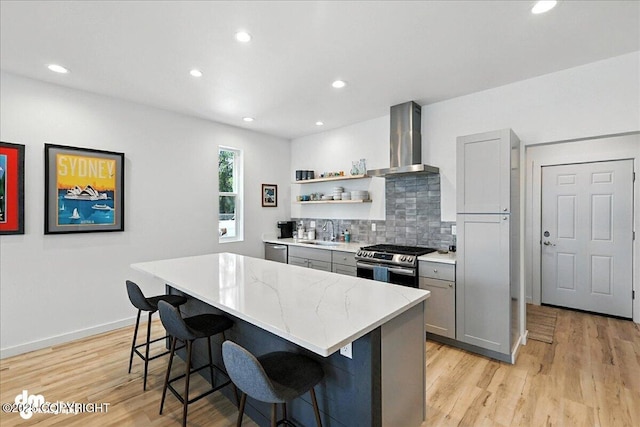 220 Susieana Ln, Kenai, AK 99611 - kitchen featuring wall chimney exhaust hood, stainless steel appliances, gray cabinets, a center island, and a kitchen bar
